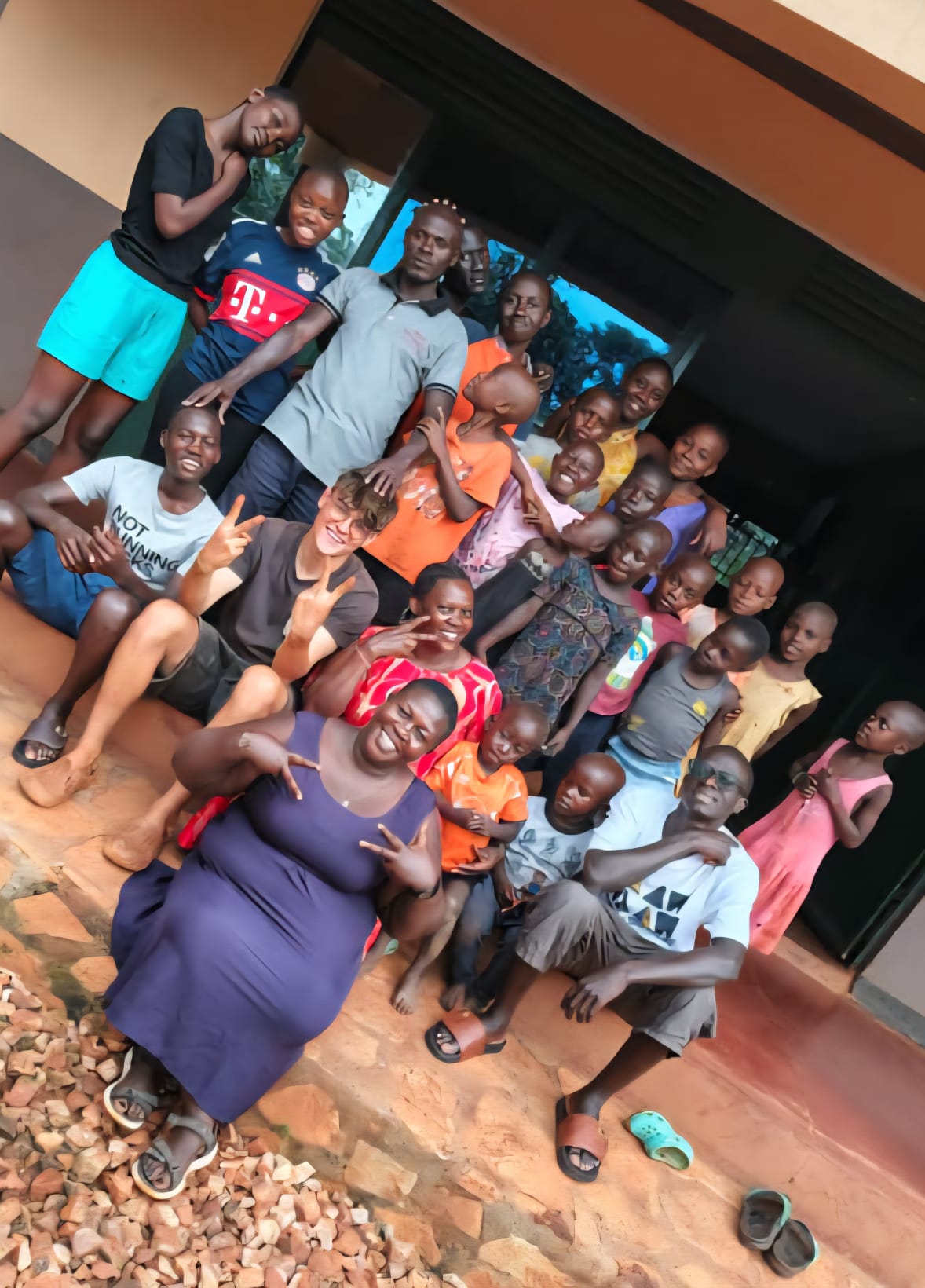 das zweite Bild zeigt Adrian Struck mit einigen Kindern und Mitarbeitenden vor dem EWAKA-Kinderheim in Uganda